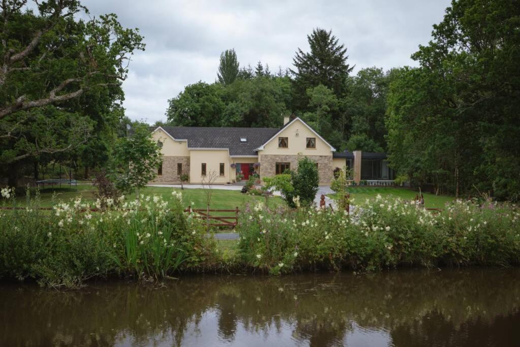 una casa con un estanque delante de ella en Canal bank house, en Bellanaboy