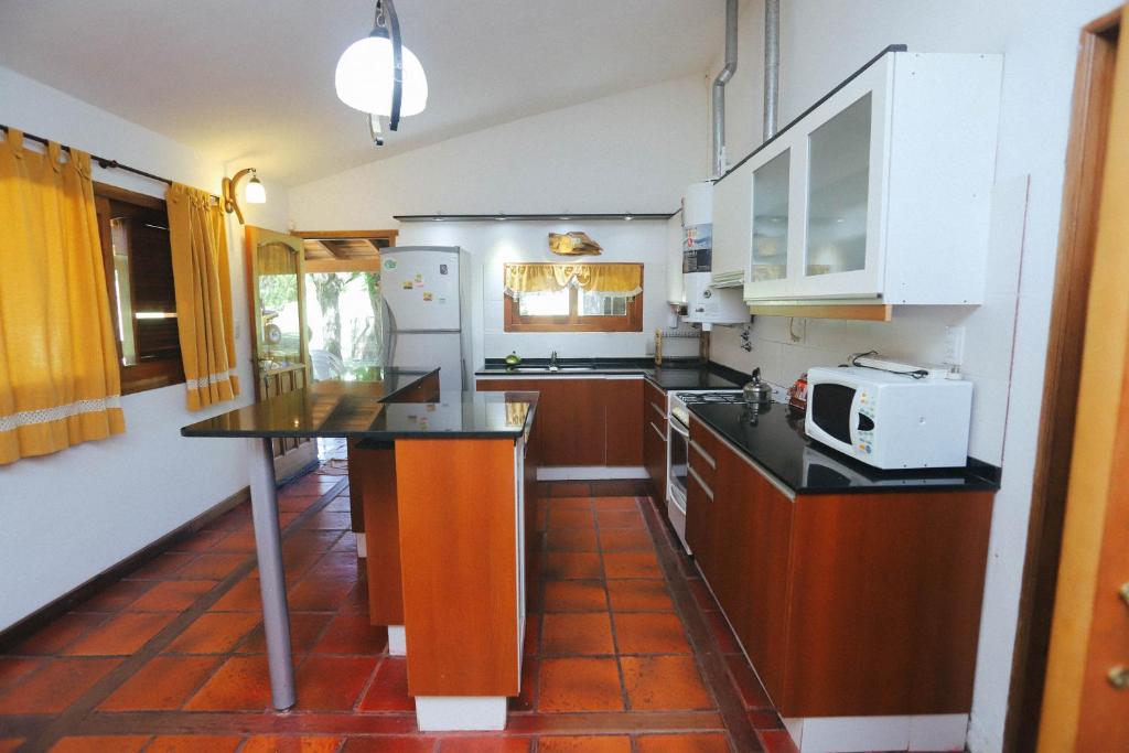 a kitchen with white appliances and a black counter top at Cabaña Modestita - FINCA PUDUAM in Villa General Belgrano