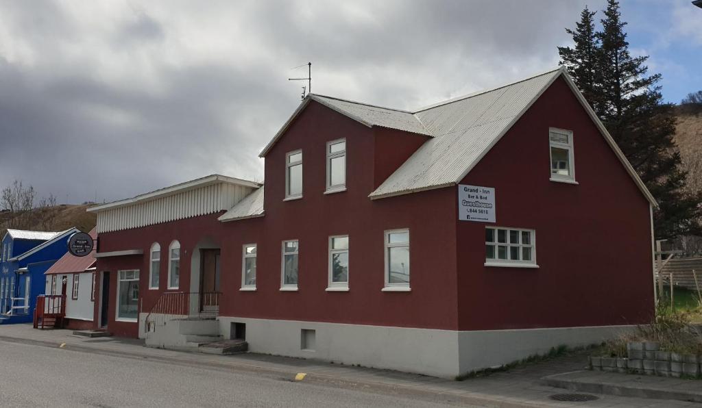 a red building on the side of a street at Grand-Inn Bar and Bed in Sauðárkrókur