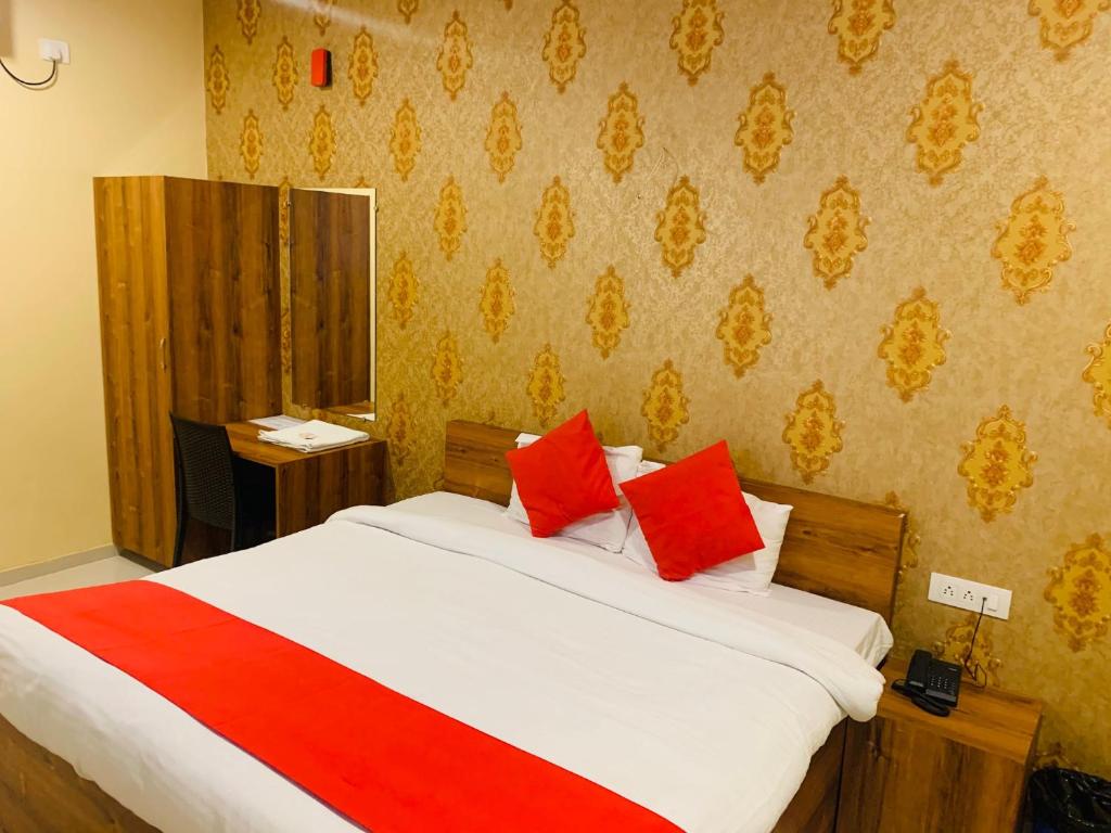 a bedroom with a large bed with red pillows at Hotel Neelkanth in Jabalpur