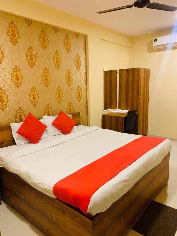 a bedroom with a large bed with red pillows at Hotel Neelkanth in Jabalpur