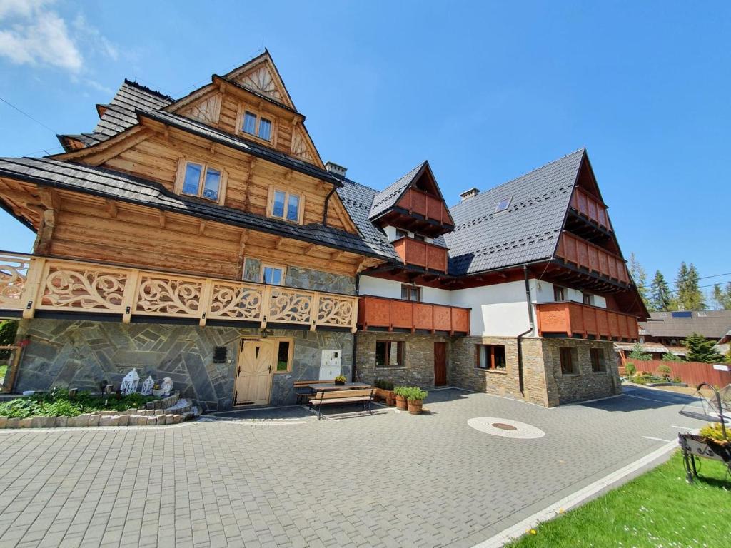 a large wooden house with a courtyard in front of it at Willa U Kantora in Murzasichle