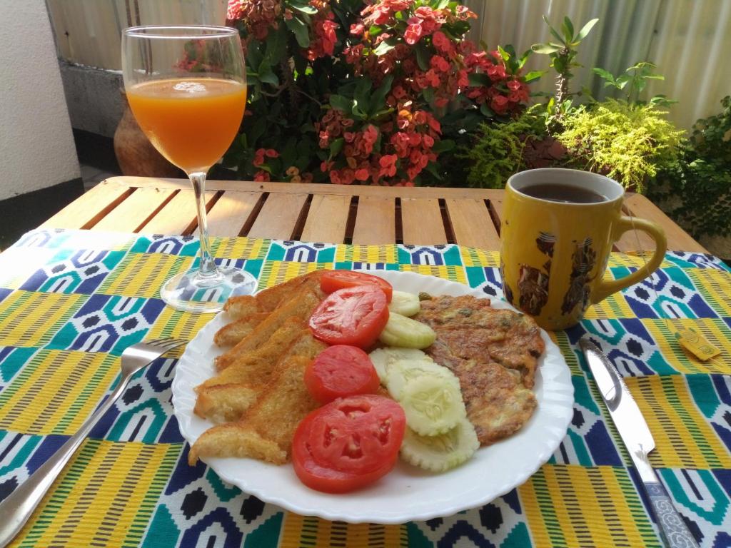 un plato de desayuno y un vaso de zumo de naranja en New Kivulini Bed and Breakfast, en Dar es Salaam