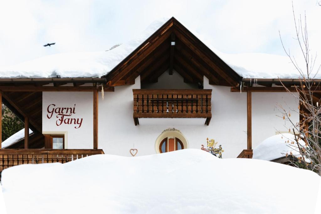 Una casa cubierta de nieve con un cartel. en Garni Fany, en Colfosco