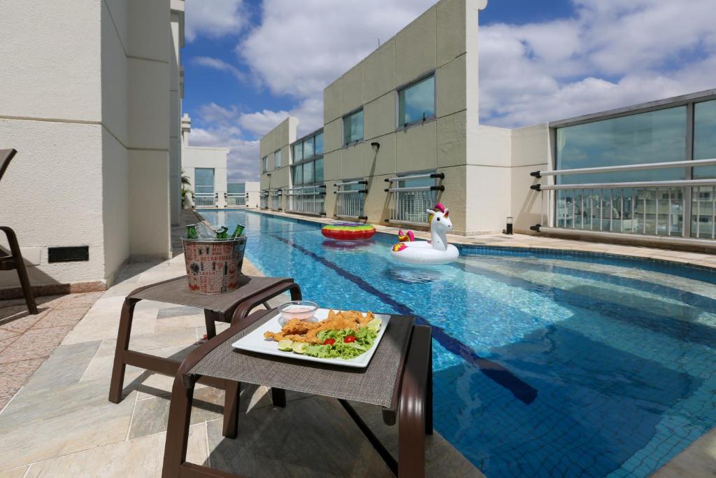 a plate of food on a table next to a swimming pool at Quality Suítes Oscar Freire in São Paulo