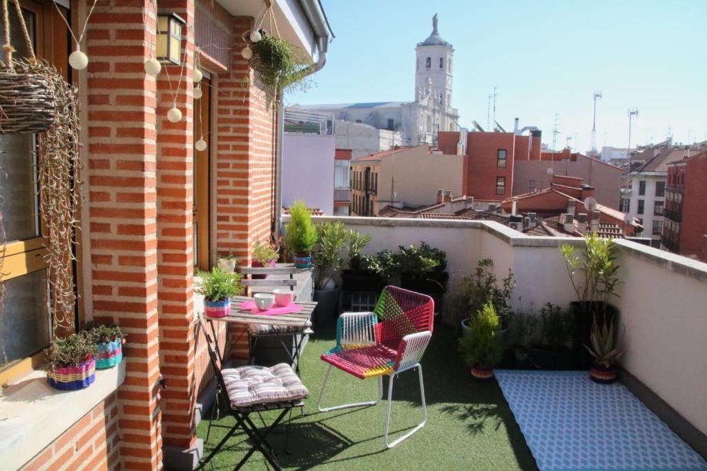 Un pequeño balcón con sillas y una mesa en un edificio en El Ático de Valladolid - Centro - Terraza - Wifi, en Valladolid