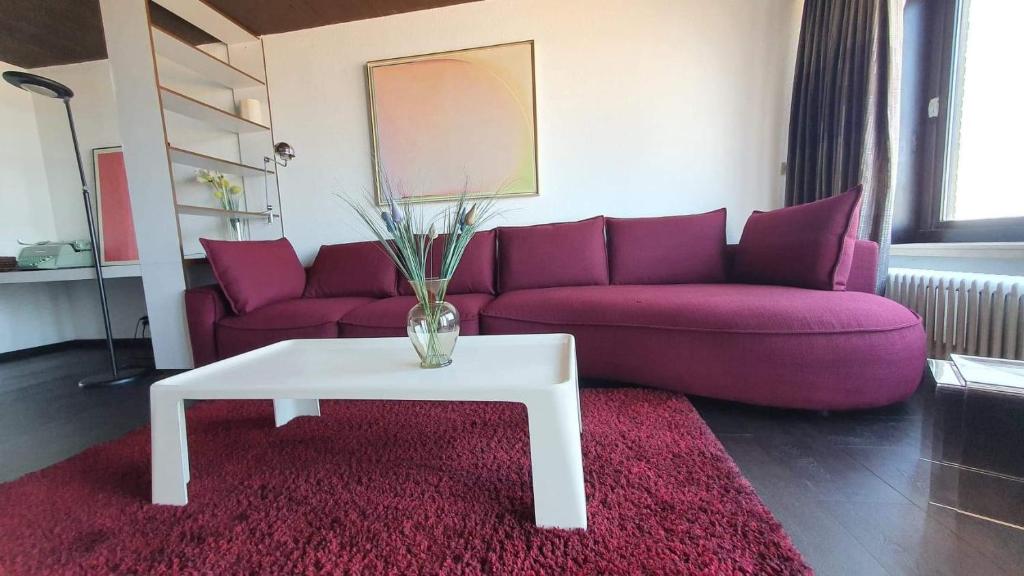 a living room with a purple couch and a white coffee table at Modern appartement met frontaal zeezicht en privé parking in Knokke-Heist