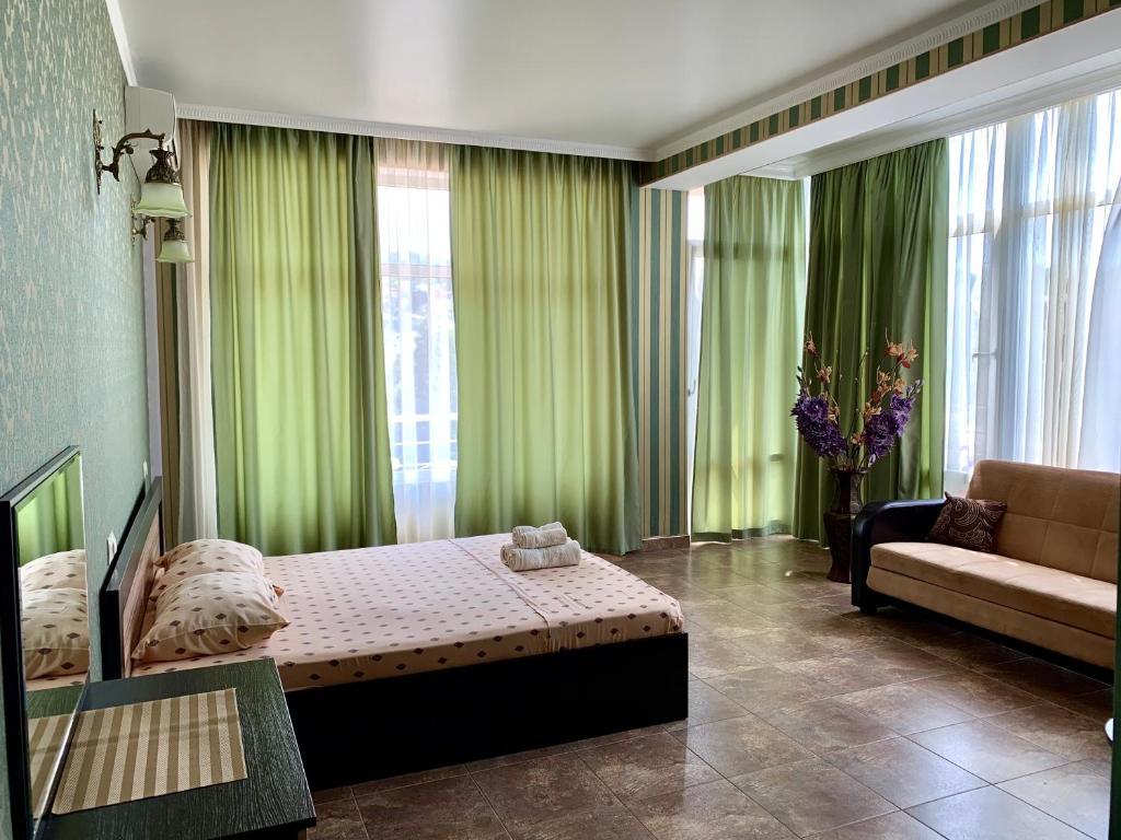 a bedroom with green curtains and a bed and a couch at Гостиница Эллада in Lazarevskoye