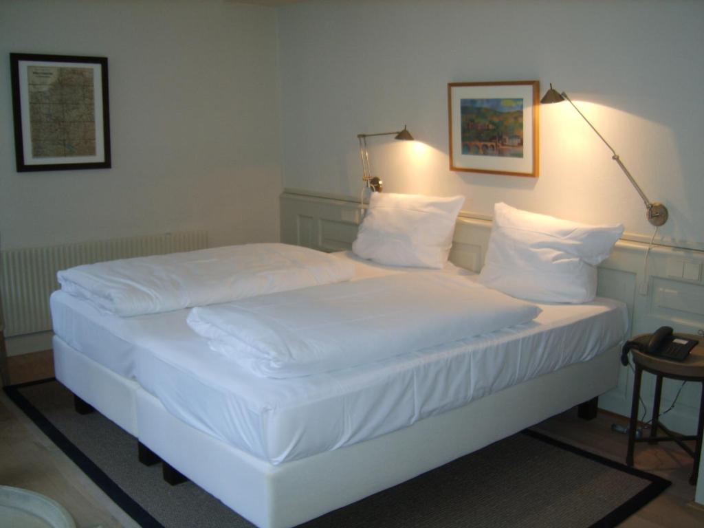 Bett mit weißer Bettwäsche und Kissen in einem Zimmer in der Unterkunft Hotel Schnookeloch in Heidelberg
