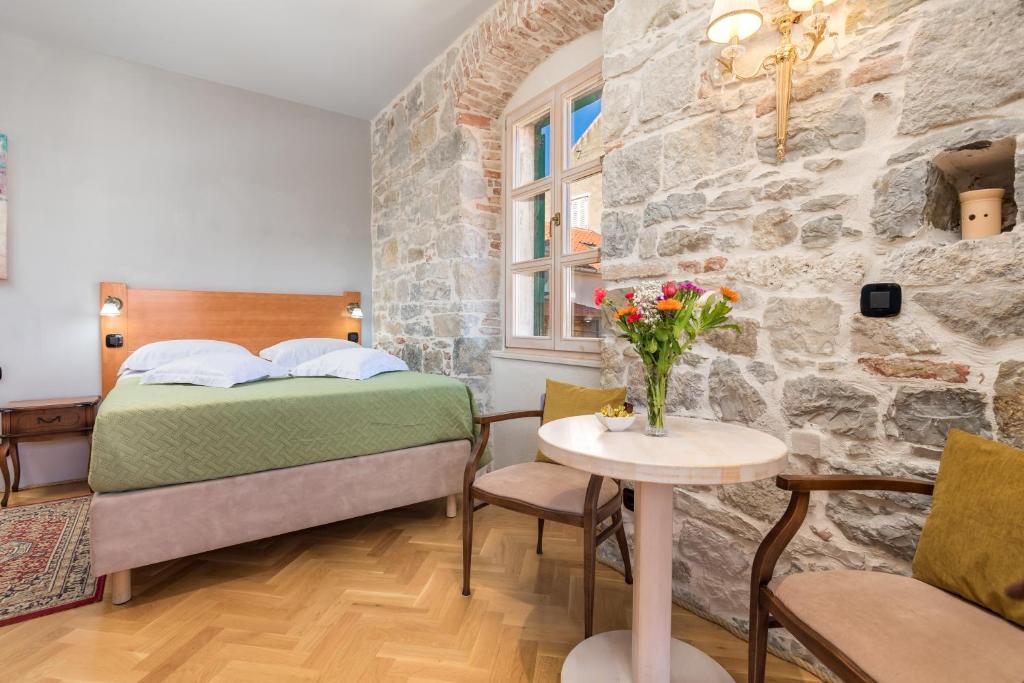 1 dormitorio con 1 cama y 1 mesa con flores en Captain's Guest House, en Split