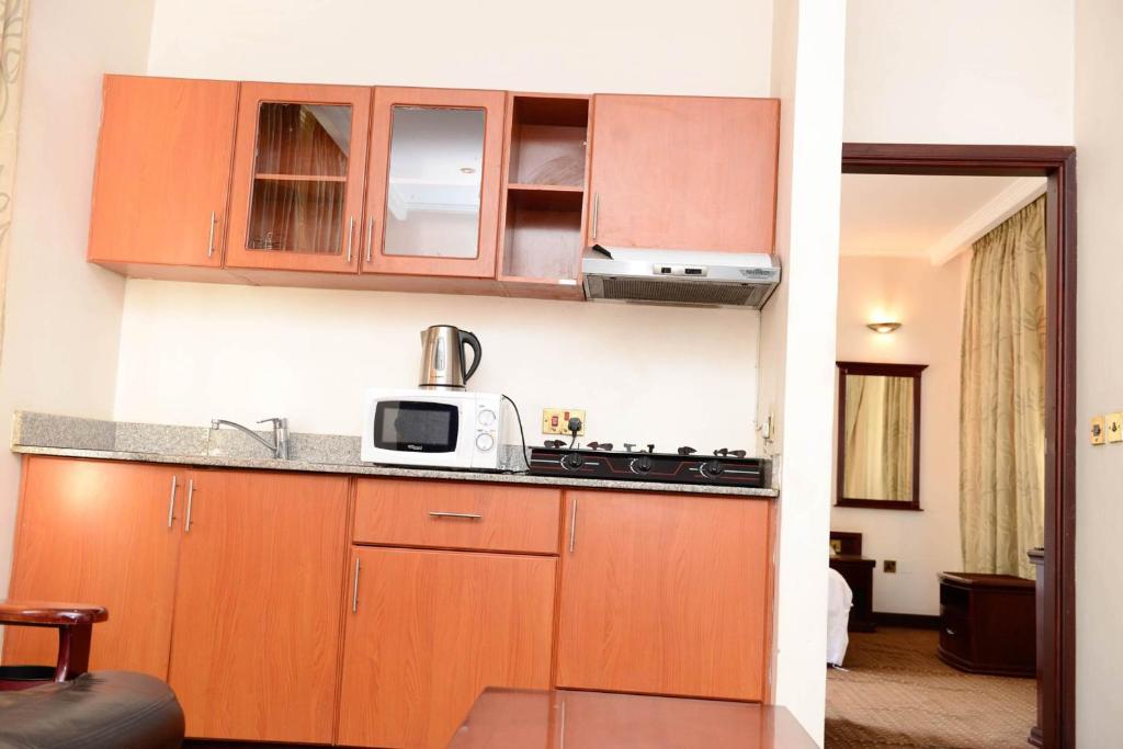 a kitchen with wooden cabinets and a microwave at Room in Apartment - This wonderful Senior Suite offers a great experience in Kigali