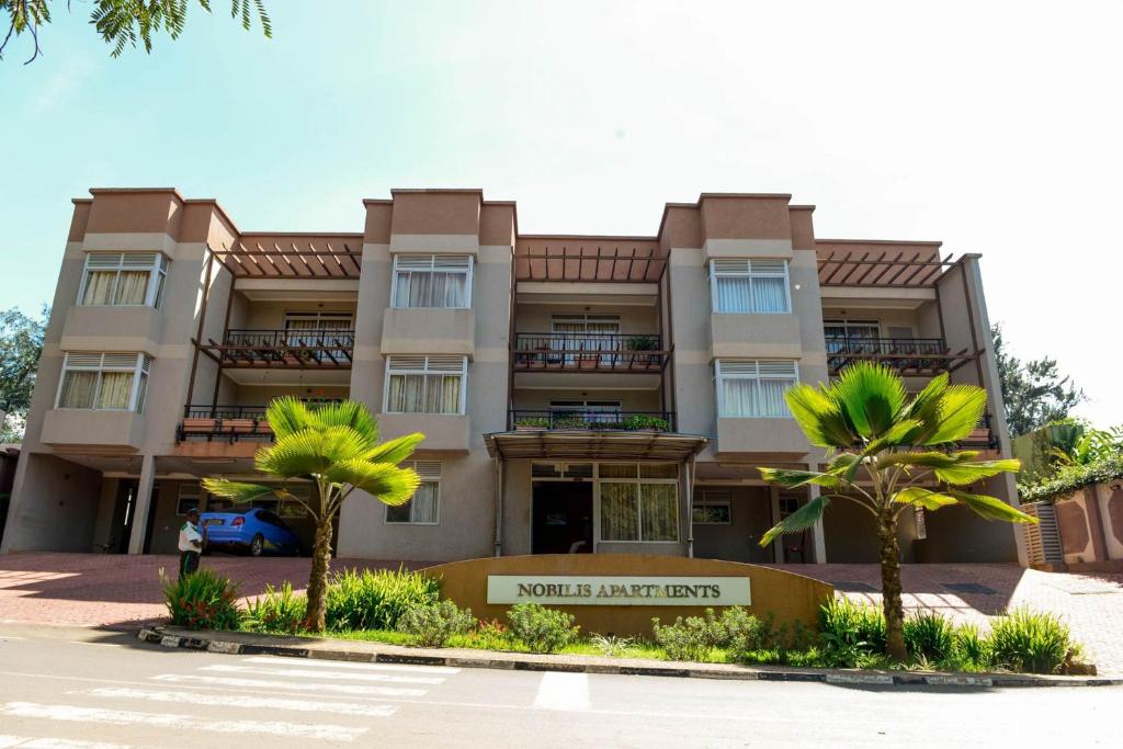 um edifício com palmeiras em frente em Room in Apartment - You will relax with the amenities offered by this Standard Suite em Kigali