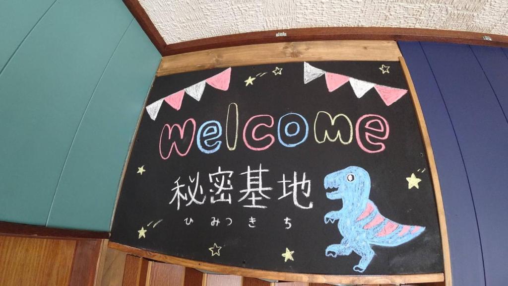 una señal de bienvenida con un dinosaurio en una pizarra en BBQ可 1日1組限定 貸切別荘 秘密基地 は恐竜博物館まで3km スキージャム勝山まで12km, en Katsuyama
