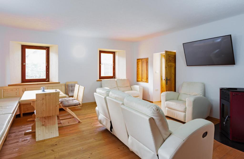a living room with white furniture and a flat screen tv at Old Farm House Breg in Žirovnica