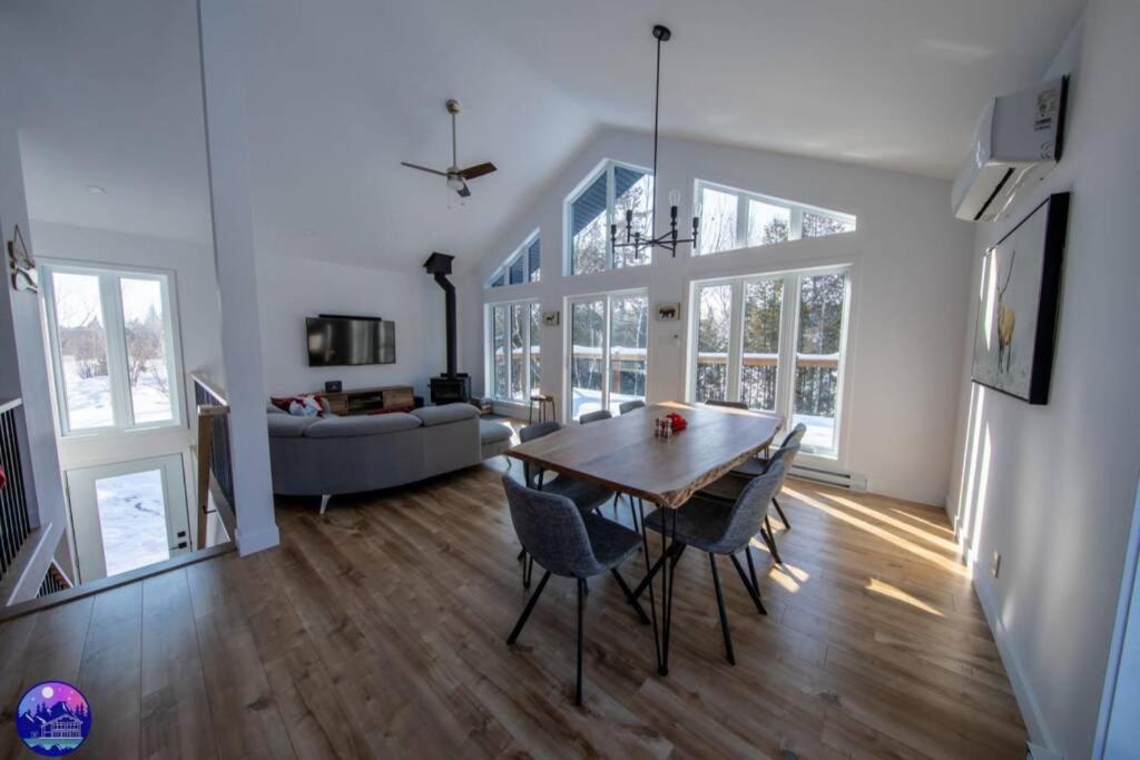 a dining room and living room with a table and chairs at Chalet le Caribou- Chalets Galaxia in Saint-Alphonse-Rodriguez