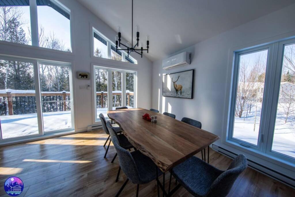 a dining room with a wooden table and chairs at Chalet le Caribou- Chalets Galaxia in Saint-Alphonse-Rodriguez