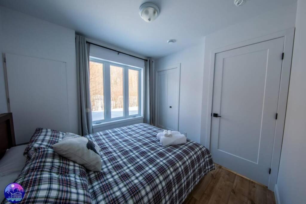 a bedroom with a bed and a large window at Chalet le Caribou- Chalets Galaxia in Saint-Alphonse-Rodriguez