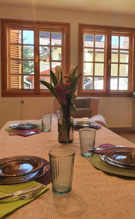 a table with plates and a vase with flowers on it at Vila Panselutelor 6 in Sinaia