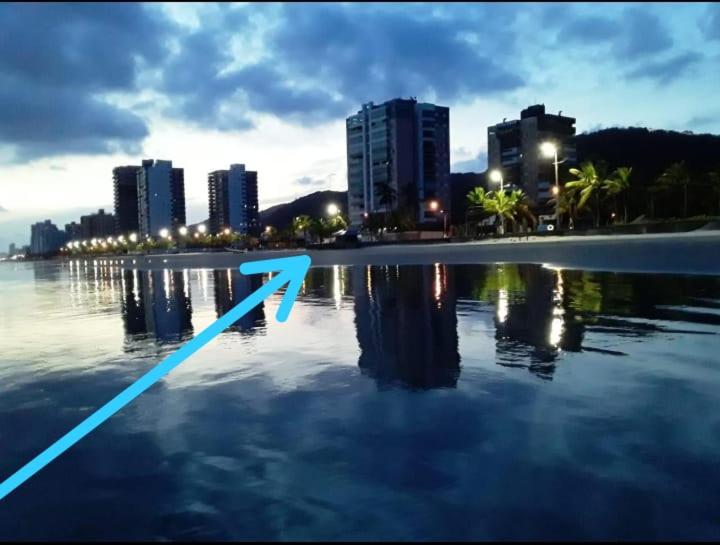 um reflexo de uma cidade na água com edifícios em Apartamento Temporada pé na areia em Mongaguá