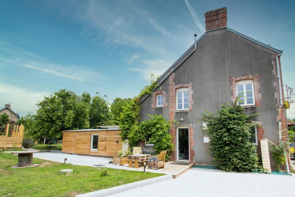 una gran casa gris con una mesa de picnic en un patio en La Maison réseau Cycle et Gites, en Clécy