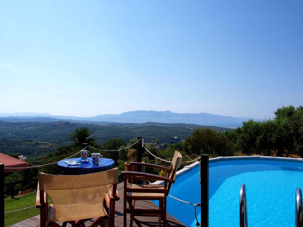 a patio with a table and chairs next to a swimming pool at Villa Papoura Homeleader in Delimanolianá