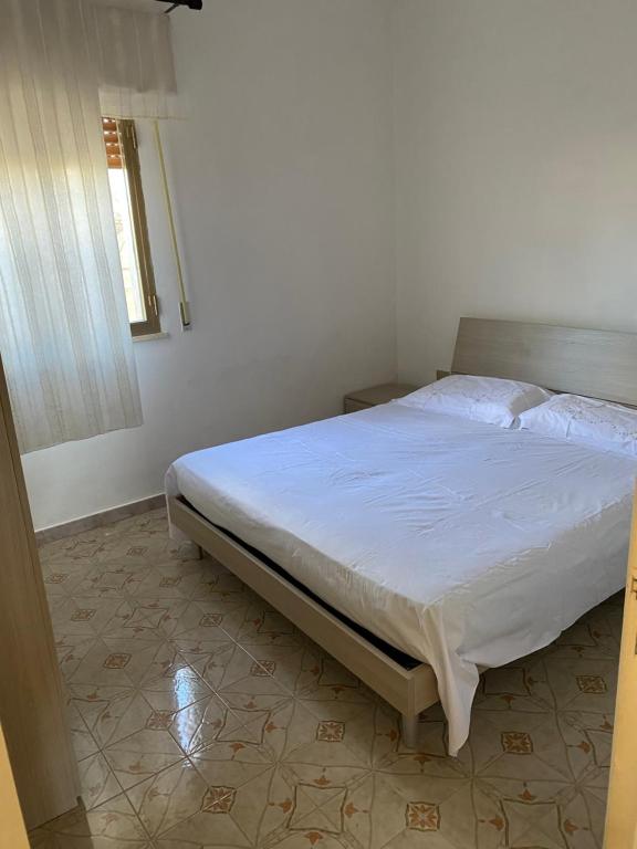 a bedroom with a bed with a white sheets and a window at Casa al mare in San Pietro in Bevagna