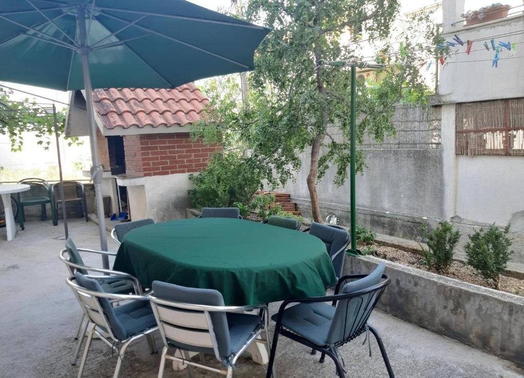 een tafel en stoelen met een groene tafel en een parasol bij Apartment Željko - large terrace in Makarska