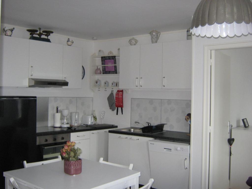 uma cozinha com armários brancos e uma mesa branca em Le Pont de l'Aure em Isigny-sur-Mer