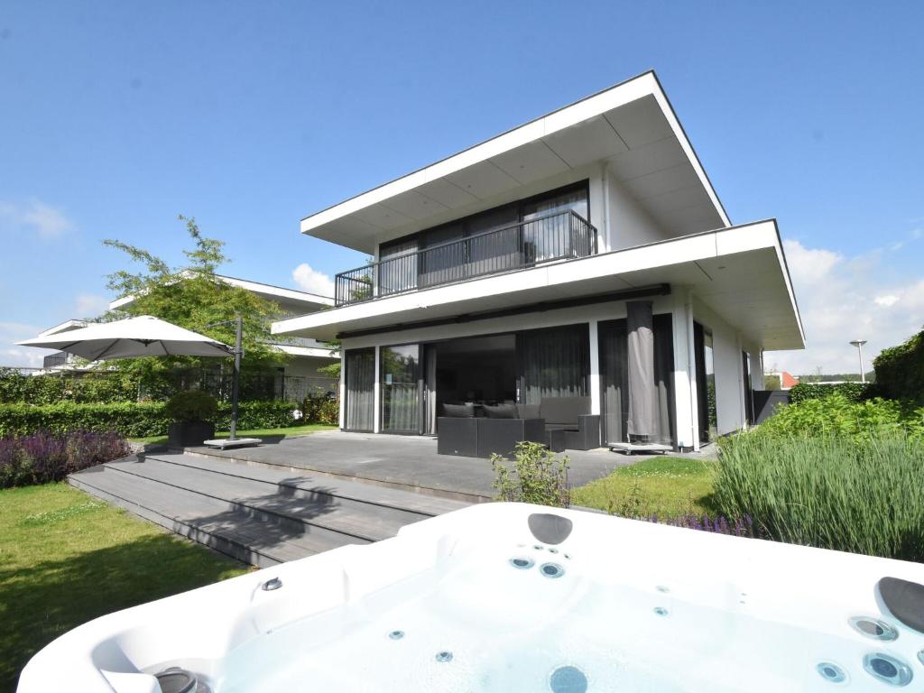 een huis met een ligbad ervoor bij Modern Villa in Harderwijk with Sauna and Jacuzzi in Harderwijk