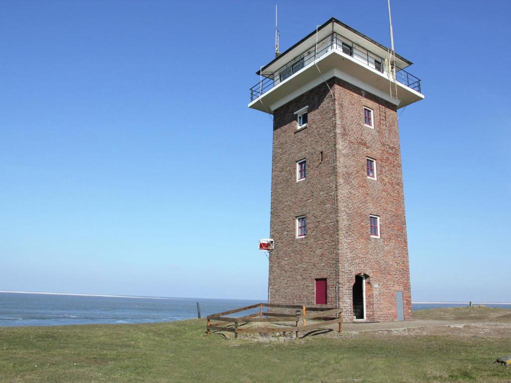 a brick lighthouse with a bench in front of the ocean at Heritage Holiday Home in Huisduinen near Sea in Huisduinen