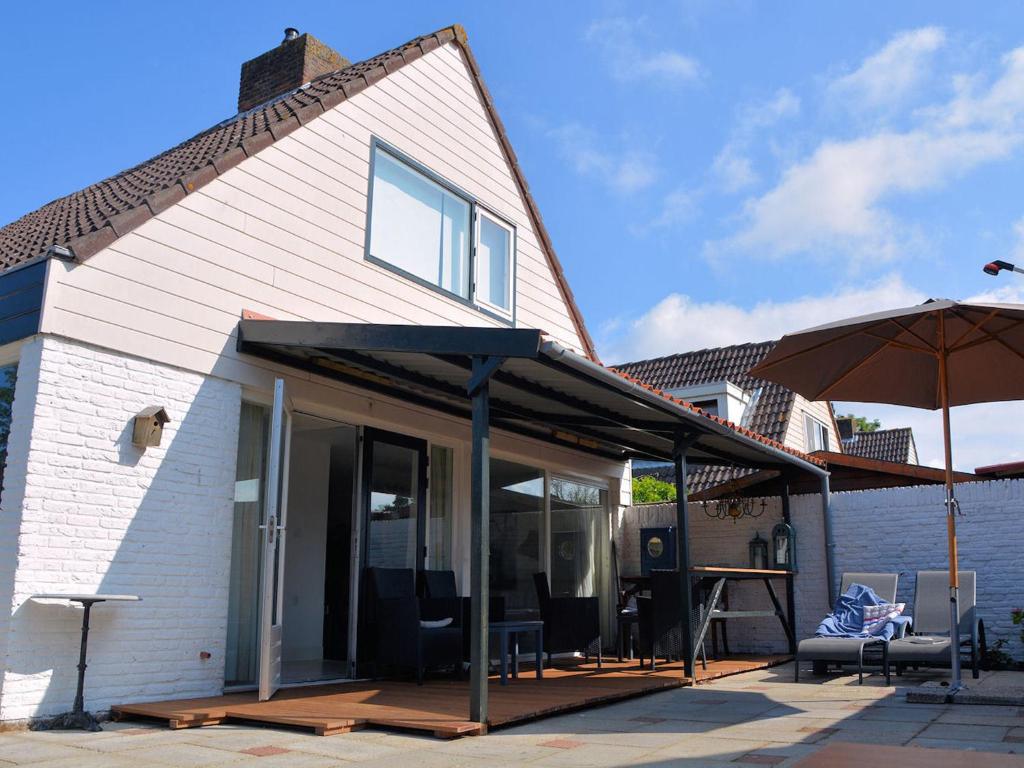 een huis met een patio en een parasol bij Lovely Holiday Home in Noordwijkerhout near Lake in Noordwijkerhout