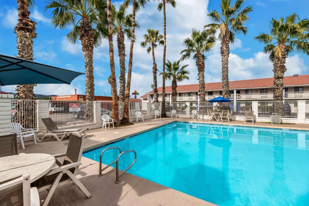 une piscine bordée de palmiers et un hôtel dans l'établissement Motel 6-Eloy, AZ - Casa Grande, à Eloy