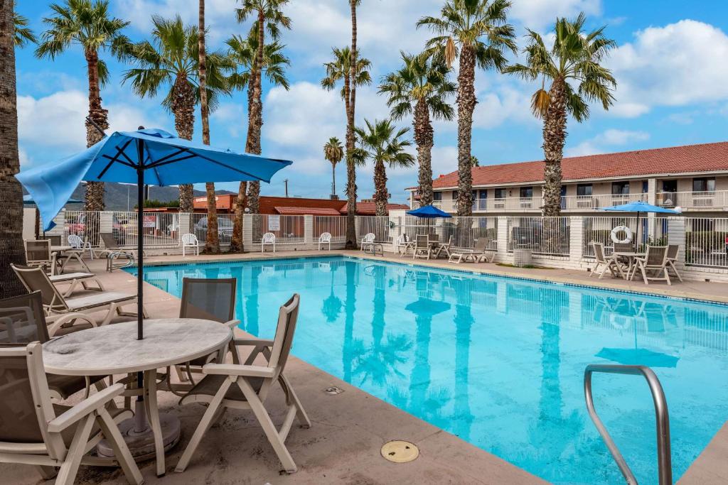 a pool with tables and chairs and palm trees at Motel 6-Eloy, AZ - Casa Grande in Eloy
