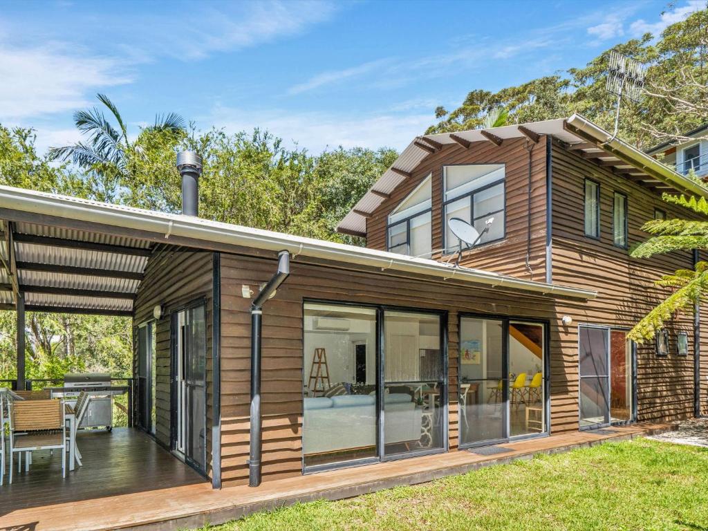 a house with glass doors and a deck at Charming Beach Home with Plenty of Outdoor Spaces in Avoca Beach