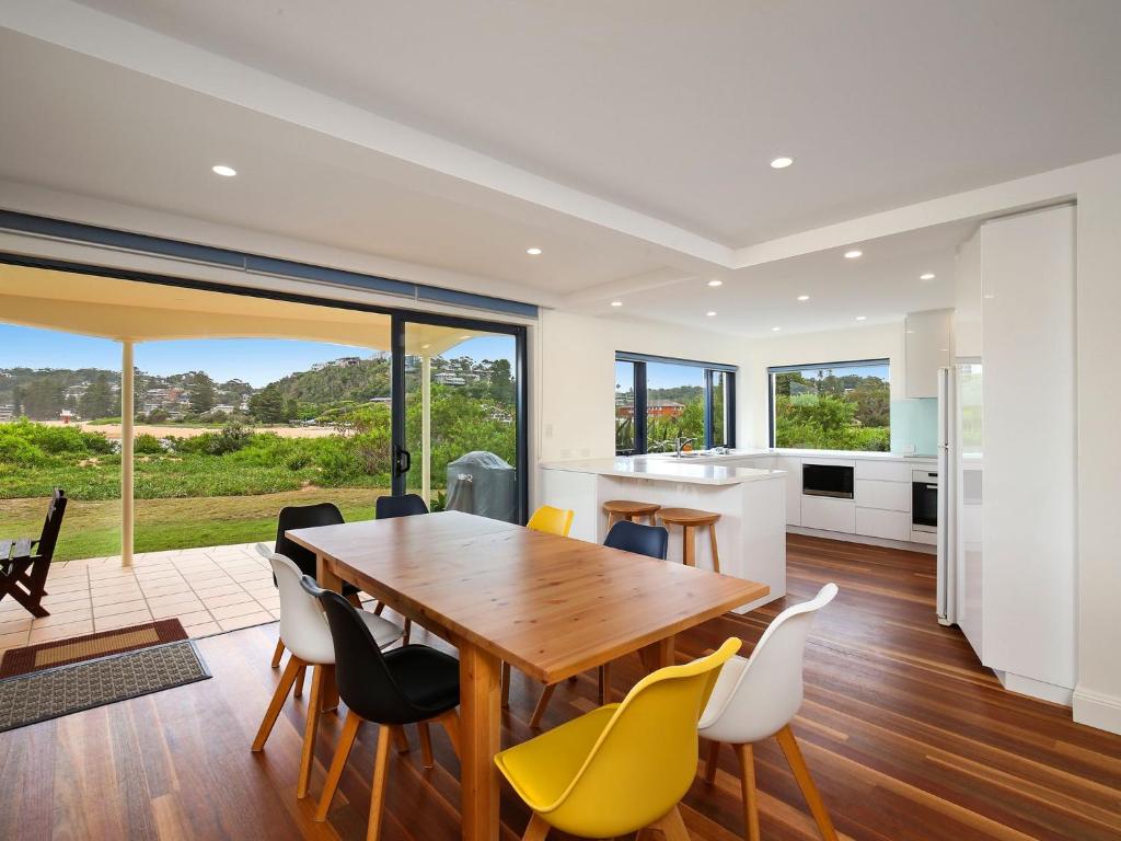 a kitchen and dining room with a wooden table and chairs at Beachfront Delight - 14b Bareena Avenue in North Avoca