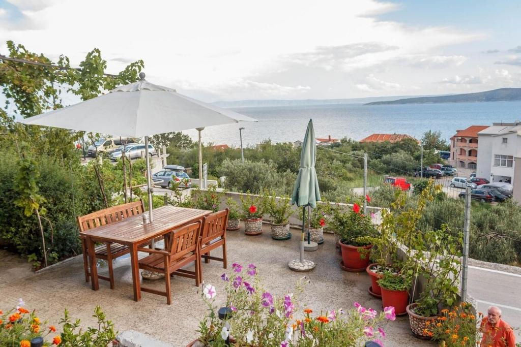 a patio with a table and umbrella and flowers at Apartments Ante - seaview in Brela
