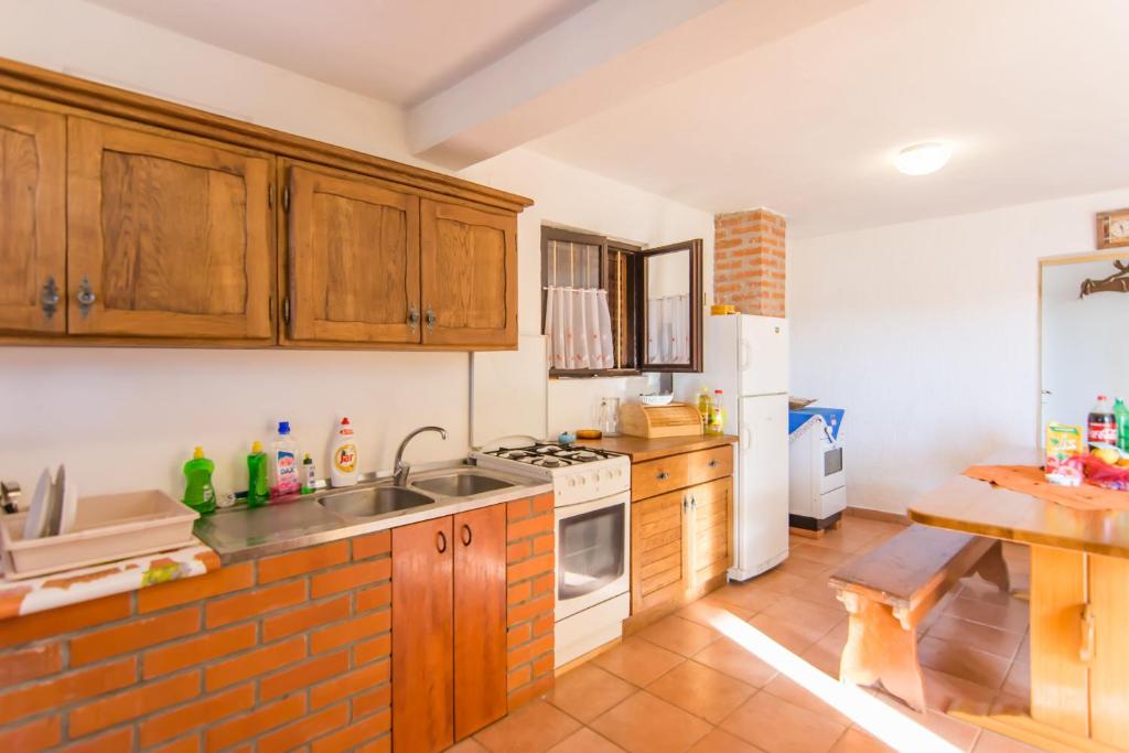 kuchnia z drewnianymi szafkami i ceglaną ścianą w obiekcie House Otusi w mieście Tkon