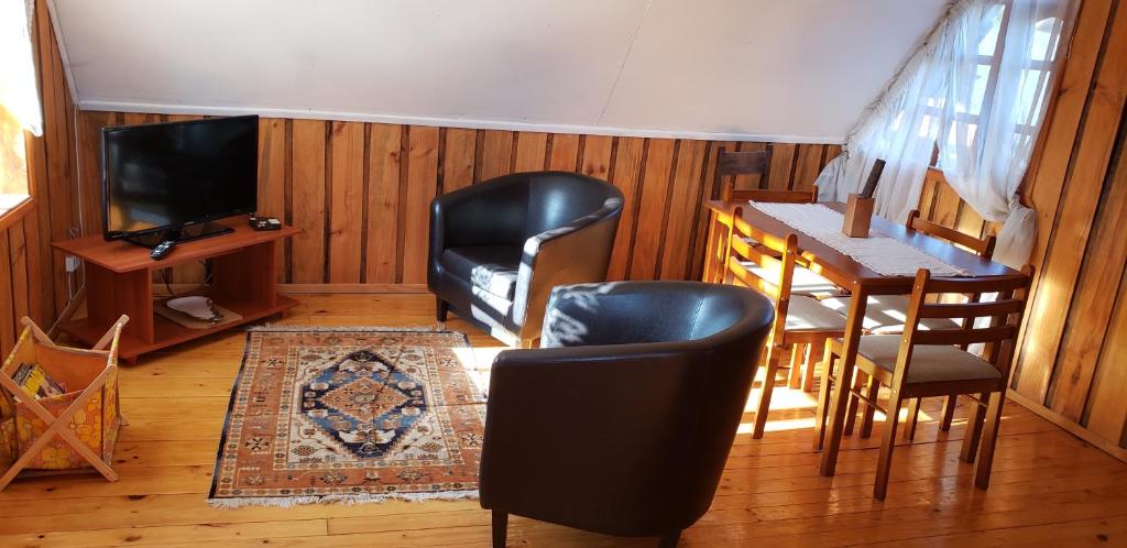 a living room with chairs and a table and a television at Cabañas cerca de Valdivia, en San José de la Mariquina in San José de la Mariquina