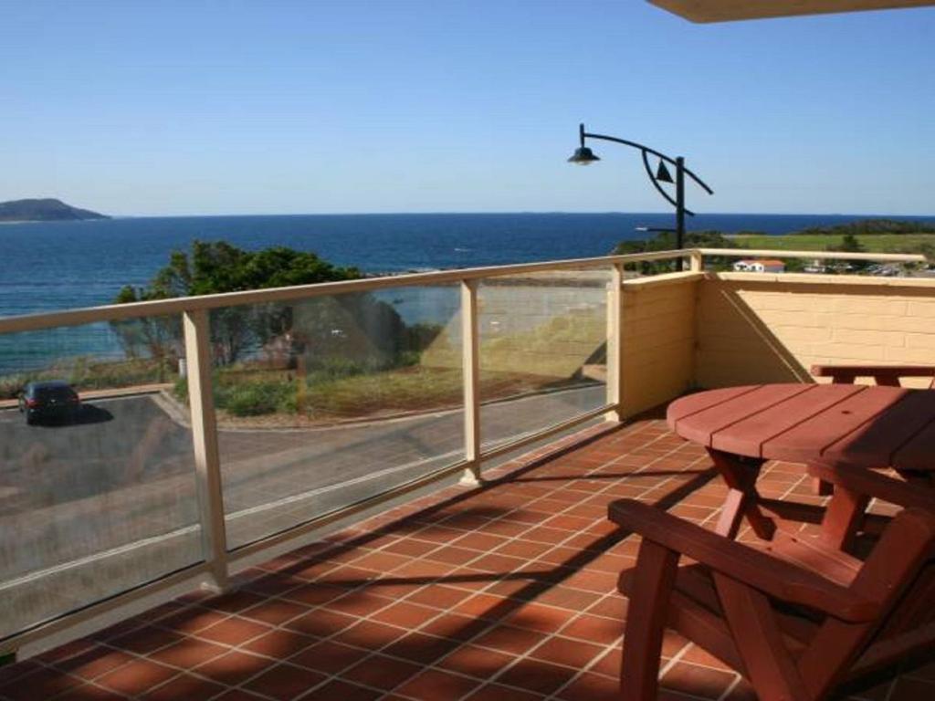 a deck with a picnic table and a view of the ocean at Charming Beach Getaway, Close to Cafe & Restaurant in Terrigal