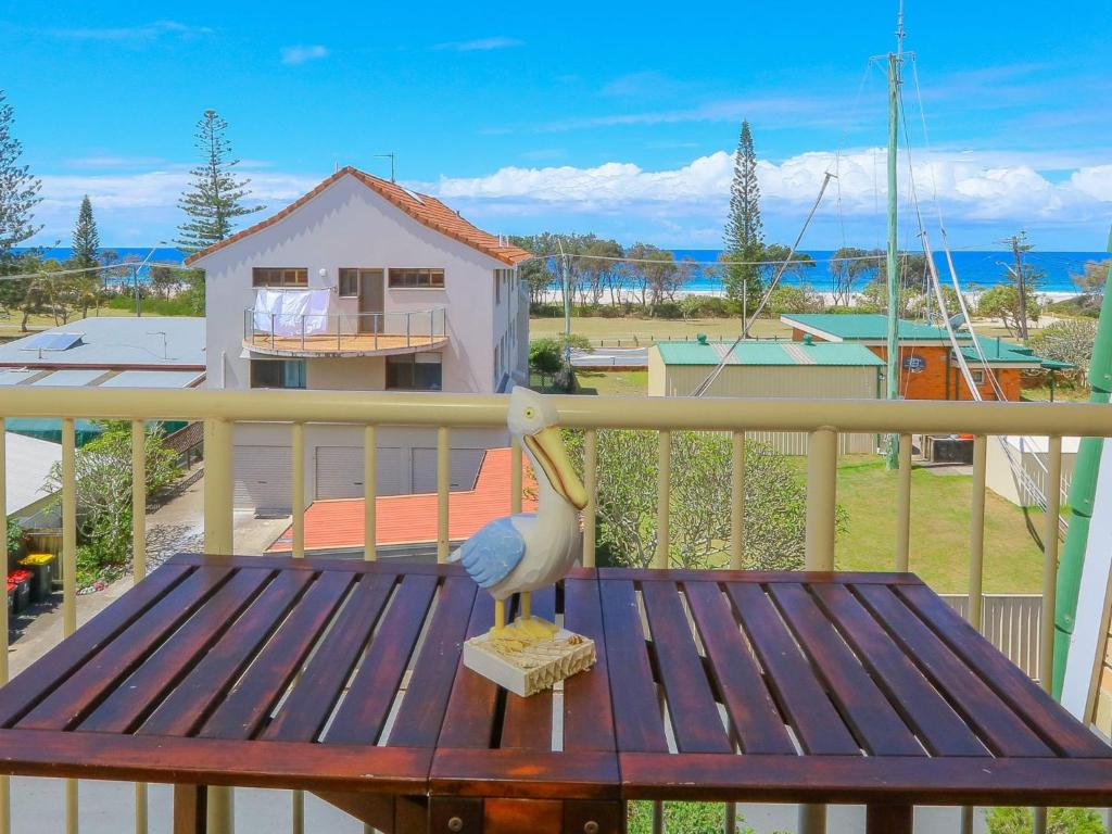 a bird statue sitting on a wooden bench on a balcony at Kingsway Apartment 12 in Kingscliff