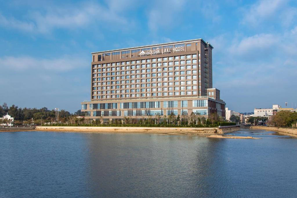 een groot gebouw naast een waterlichaam bij Golden Lake Hotel in Jinhu