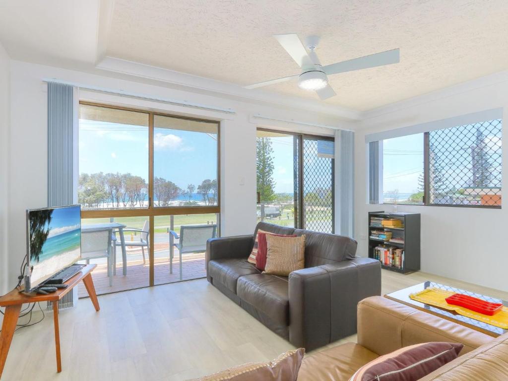 a living room with a couch and a television at Acacia Holiday Apartment in Kingscliff