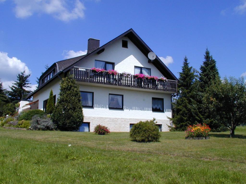 a large white house with flowers on a balcony at Haus - Pantenburg in Manderscheid