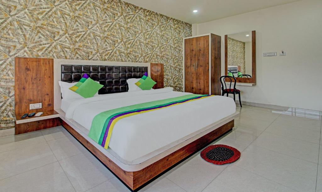 Schlafzimmer mit einem großen Bett mit einem Kopfteil aus Holz in der Unterkunft Treebo Trend Golden Heights in Jamshedpur