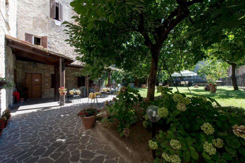 a courtyard of a building with a tree and flowers at Residenza Di Via Piccardi in Gubbio
