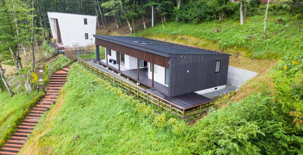 uma casa numa colina com um edifício sobre ela em Koti Yamanakako next to Hananomiyako Kouen em Yamanakako