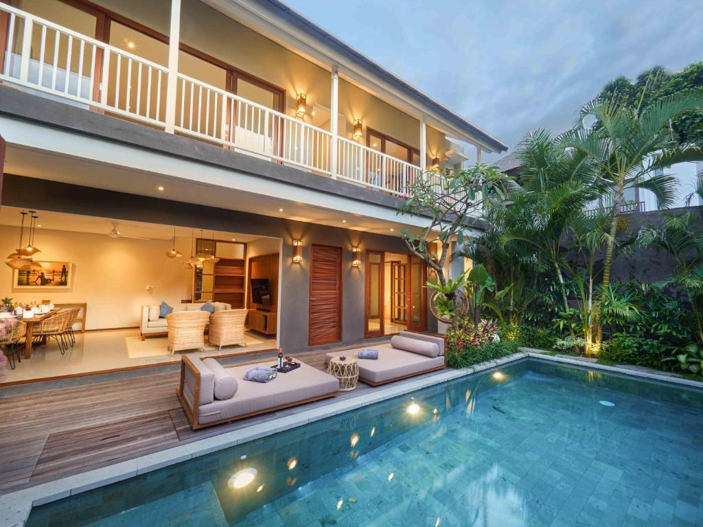 a villa with a swimming pool in front of a house at Agra & Amurti Villas in Munggu