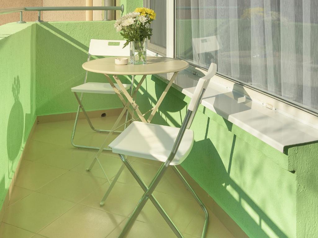 a table with two chairs and a vase of flowers at Like home in Burgas City