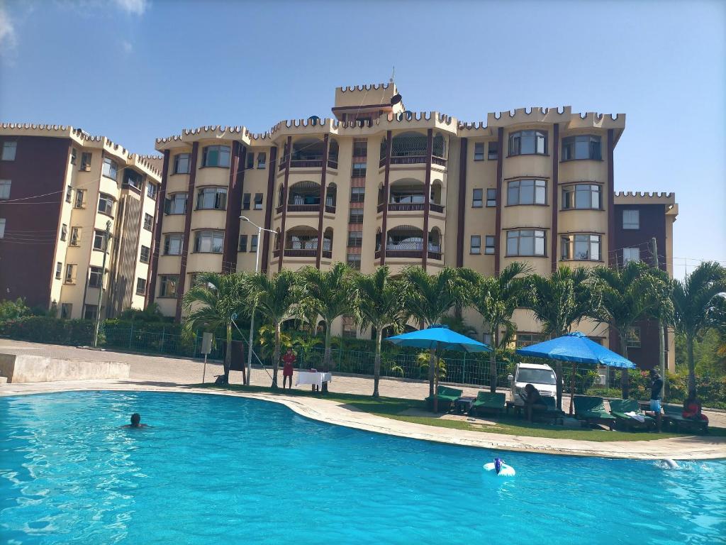 a swimming pool in front of a large building at FASTCARE Mj APARTMENTS And VILLAS in Mombasa