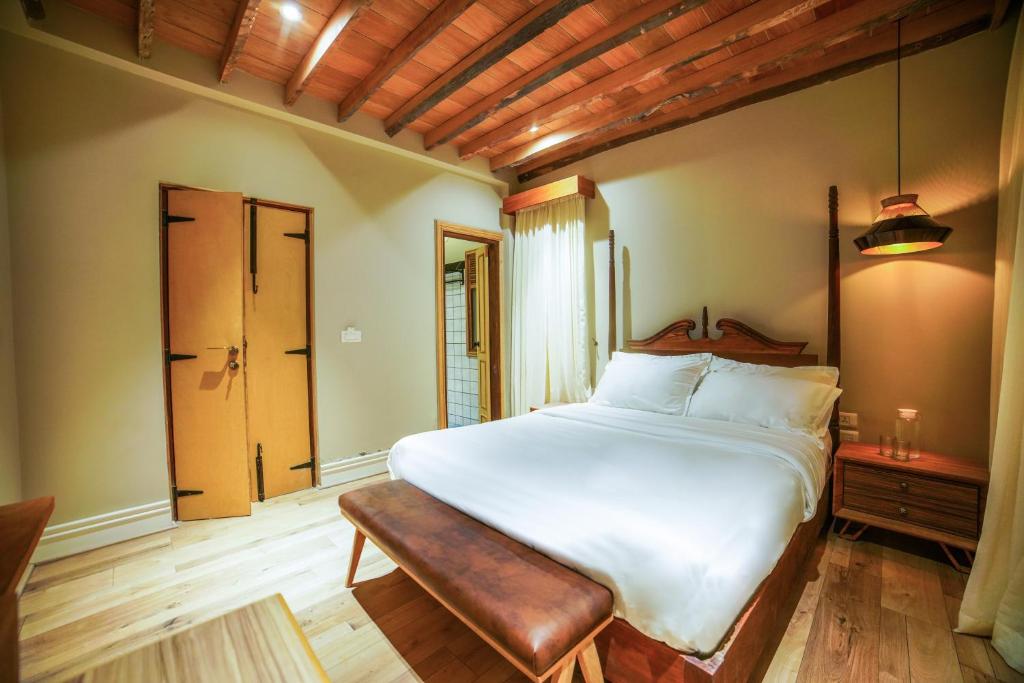 a bedroom with a large white bed and a bench at Meraki maison in Ooty